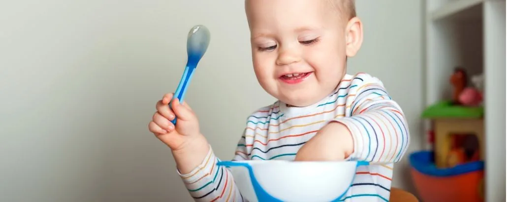 Toddler eating from a bowl with a spoon