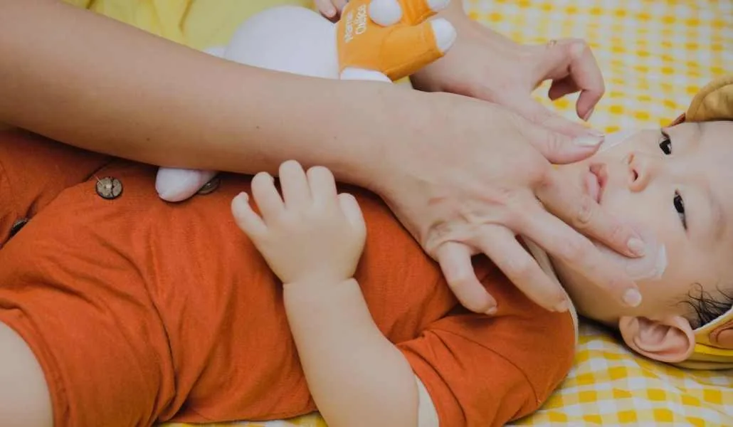 Ibu memakaikan sunblock ke anak