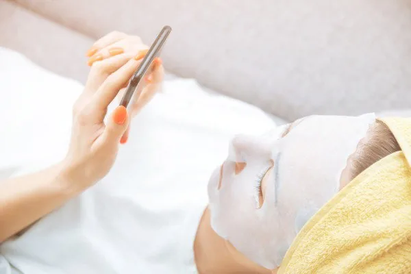 Perempuan memakai sheet mask saat perawatan wajah