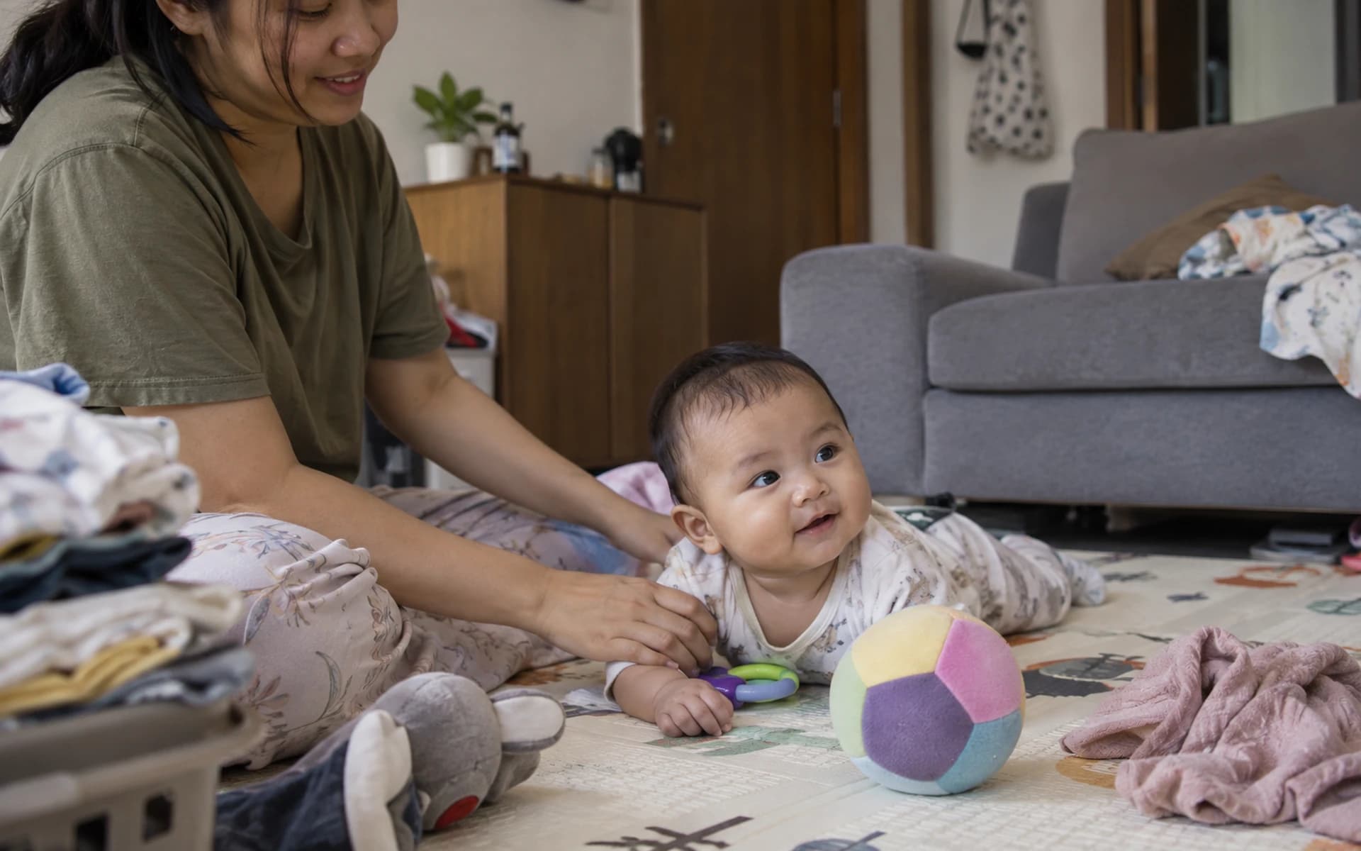 Bayi bermain di lantai bersama orang tuanya di rumah